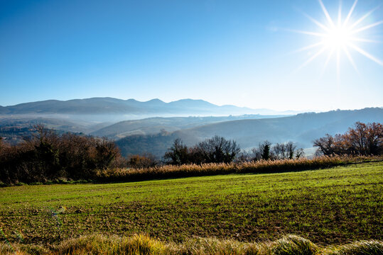 Sunlit field with hills and vegetation in Italy