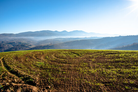 Cultivated field with hills and distant mountains in Italy