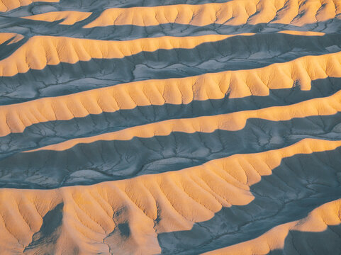 Aerial view of the eroded ridges and badlands of Factory Butte under golden hour light in Wayne County, Utah, United States.