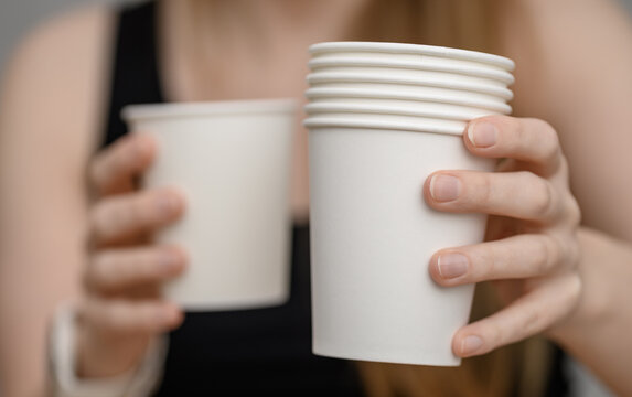 Disposable white drinking cups held in hands, sup