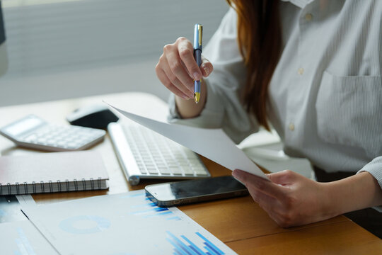 Woman holding pen reviewing business document financials