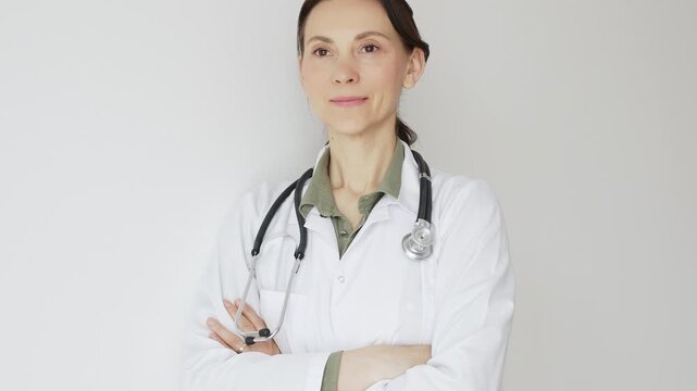 Female medical professional in white lab coat, stethoscope draped, standing with crossed arms and displaying confident, authoritative healthcare demeanor. Medicine and health care