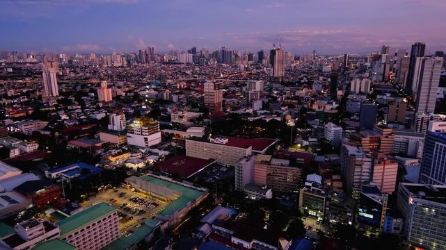 Static aerial cityscape view overlooking vast capital city of Manila, Philippines during dusky sunset with urban skyline