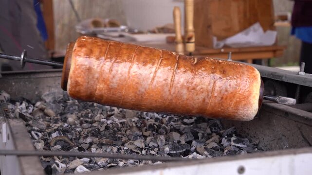 K&uuml;rtőskal&aacute;cs rotating over hot coals, baking traditional Hungarian sweet dough