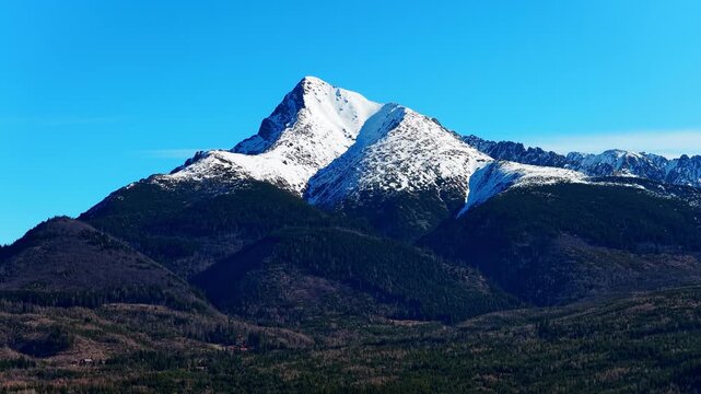 Close view of famous Kriv&aacute;ň peak in High Tatras, Slovakia. Snow covered mountain ridge above forest landscape under clear blue sky. Iconic Slovak symbol ideal for travel and nature themes.