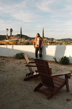 Ginger man in flannel and beanie in desert house yard at golden hour