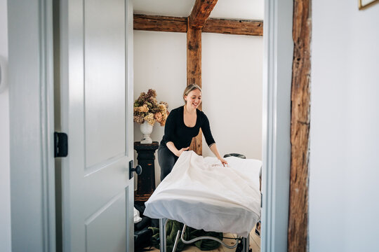Female massage therapist preparing table for wellness treatment