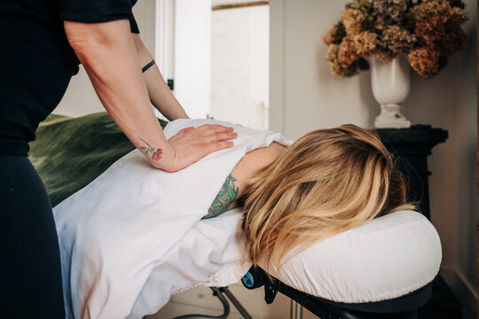Professional therapist giving back massage to woman