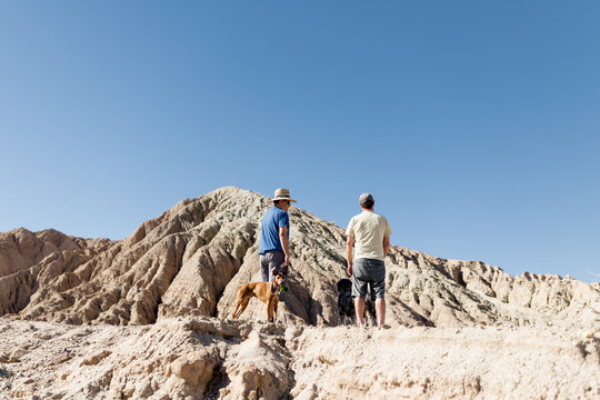 Two Middle Aged Men Standing with Dogs in Desert in CA