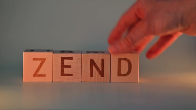 A hand moves wooden blocks to change the word from zen to zend and finally to end. The activity occurs against a soft, illuminated background, showcasing the simplicity of word formation