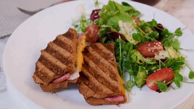 Rotating plate with grilled cheese and ham sandwich and fresh salad