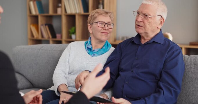 Seniors couple advisor consultation meeting planning contract. Advisor reviews terms on tablet at home and clearly answers client questions. Strong trust and successful planning outcome.