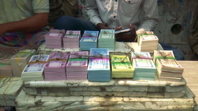 Stacks of colorful currency notes arranged on table, representing financial activity, wealth management, and organized cash handling in business setting