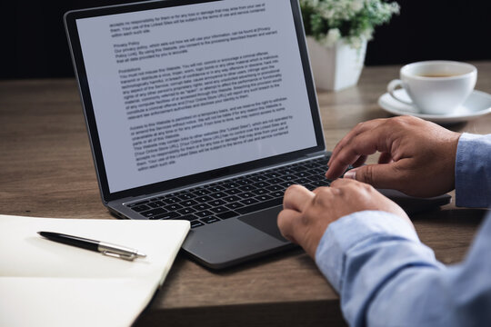 Hands typing on laptop with text document on screen at desk workspace, creating online content through writing, editing and publishing process for digital communication and remote productivity tasks.