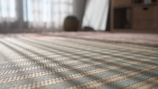 Sunlight rays casting striped shadows on a woven floor mat in a bright, tranquil room.