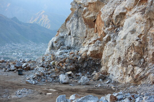 Aerial perspective of the sprawling white marble quarries in the Buner District of Pakistan, showing excavated mountainsides and deep valleys under a hazy evening sky.