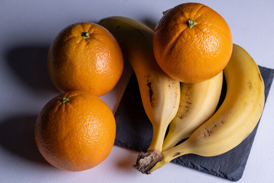 Oranges and bananas arranged on a table with natural light. Healthy fruits, colorful composition and minimal style for nutrition and food concepts.