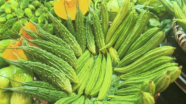 Fresh organic bitter gourd and green okra or lady's finger displayed together at a traditional Asian vegetable market