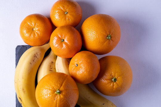 Top view of oranges and bananas on a table. Fresh fruits, natural light and clean minimal composition ideal for healthy food and nutrition concepts.