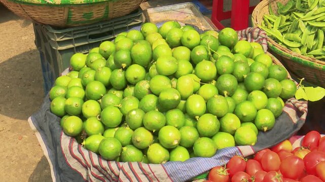 Large pile of fresh green lemons or limes displayed for sale at a traditional local market in Bangladesh