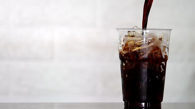 4K Close-up of iced coffee mixed with milk creating beautiful swirl texture Refreshing beverage, Concept ideal for cafe drink menu.