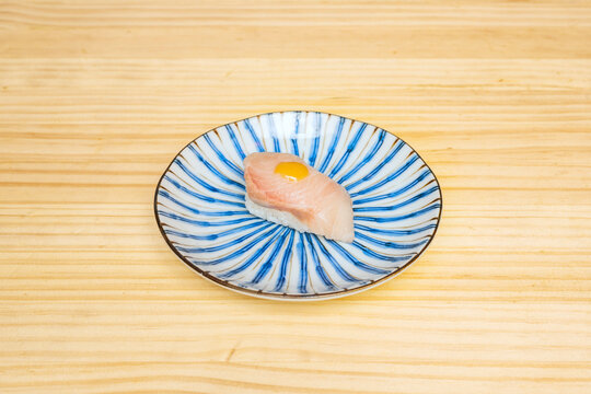 The faint smoke still rising from a freshly glazed anago (sea eel) nigiri spirals upwards, as the chef places a single grain of sansho