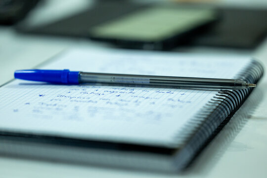 Close-up of a notebook with a pen on a desk. Writing, planning and workspace concept with minimal composition and natural light.