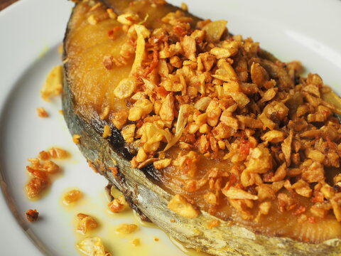 golden crispy garlic on top of fried king mackerel fish