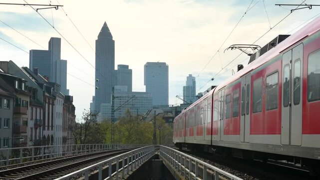 Commuter train passing railway tracks near Frankfurt West station with city skyline and financial district skyscrapers in background