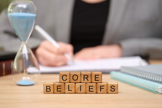 A person engages in deep reflection and writing at their desk, focusing on core beliefs. An hourglass signifies the value of time in personal growth and understanding.