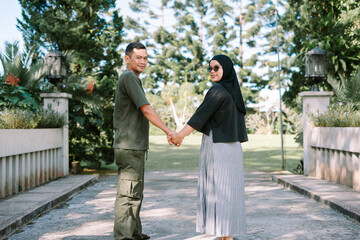 Fototapeta premium Couple from behind looking back at camera on bridge, romantic journey concept