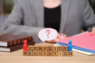 Obraz premium Individuals engage in a thoughtful dialogue about conflict resolution using colorful figures and blocks on a wooden table. Files and legal books hint at a serious discussion.