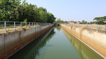 Fototapeta premium Concrete water canal. Concrete wall irrigation canal receives water in the rainy season and delivers water from the reservoir to agricultural areas during the dry season in Thailand with selected focu