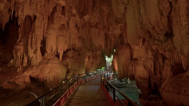 Smooth push forward towards a cave entrance before a pan and tilt down to look at the water and the walkway behind the camera