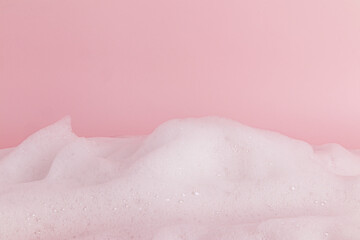 Fototapeta premium Chic white fluffy foam, soap foam texture, shampoo on a pink background. Layout for advertising detergents, spa cosmetics. Front view. A copy space