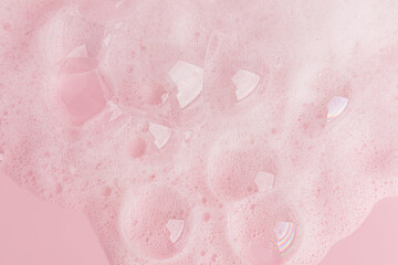 Fototapeta premium Large transparent soap bubbles, soft foam of soap, gel, detergent on a pink background. Hygiene and cleanliness concept. Top view. A copy space