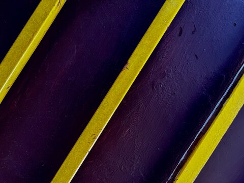 Abstract Composition of Parallel Yellow Lines on a Dark Purple Textured Surface