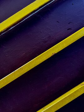 Abstract Composition of Parallel Yellow Lines on a Dark Purple Textured Surface