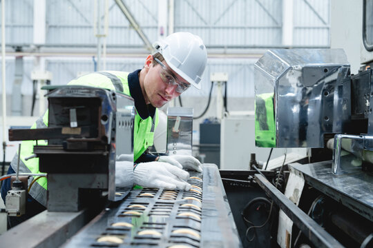 Technician meticulously inspects complex metal rack with white gloves in dimly lit industrial environment, emphasizing quality control and focused attention during machinery maintenance.