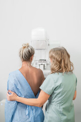50-year-old woman undergoes mammography procedure on special medical equipment mammograph with help of assistant in modern clinic. Regular medical examination, screening for breast cancer back view © illustrissima