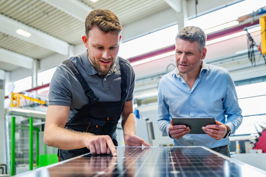 Engineer and supervisor inspecting solar panel indoors with tablet