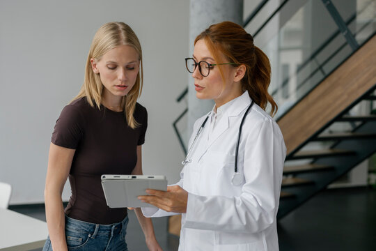 Doctor explaining examination results to patient using tablet indoors