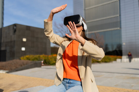 Woman using virtual reality headset outdoors in urban setting