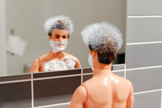 Doll with foam on face and chest in bathroom mirror parody scene
