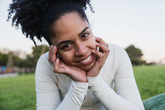 Smiling woman with curly hair posing outdoors in a park