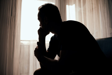 Silhouette of depressed, sad and lonely man in the apartment.