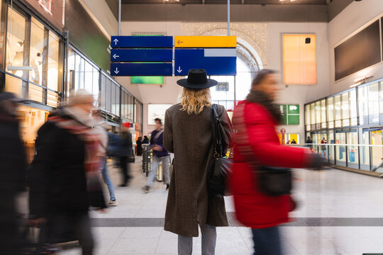 Young man waiting at urban train station with people in motion blur