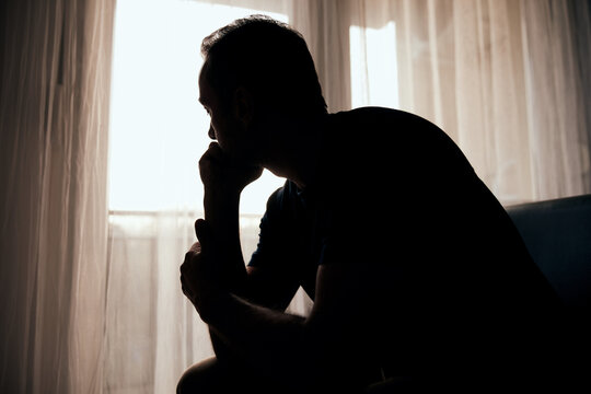 Silhouette of depressed, sad and lonely man in the apartment.