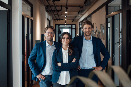 Confident business team standing together in modern office corridor
