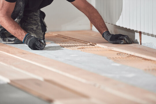 Professional handyman installing laminate flooring in a new apartment.